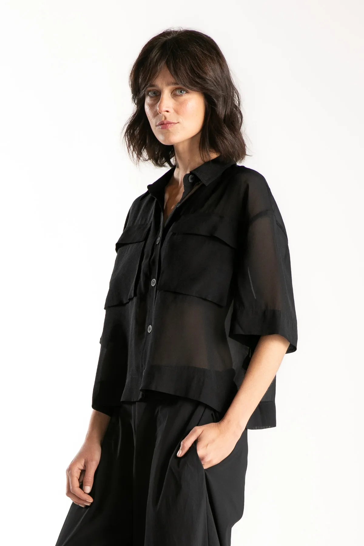 Ragga blusa Adira camisera en textil translúcido negro manga corta bolsillos de parche vista perfil