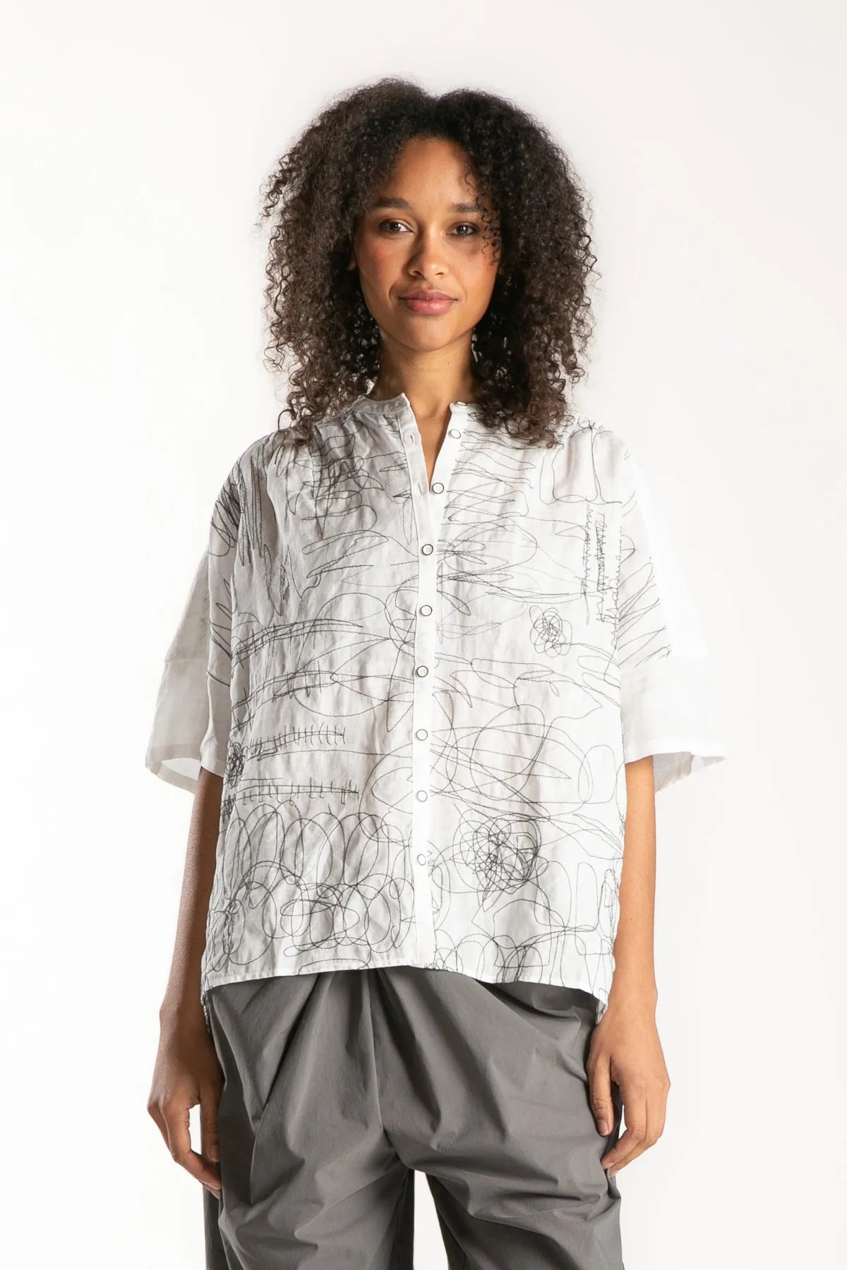 Ragga Blusa Frisia mao manga corta de mujer en ramio blanco con bordado figuras grafito vista frontal