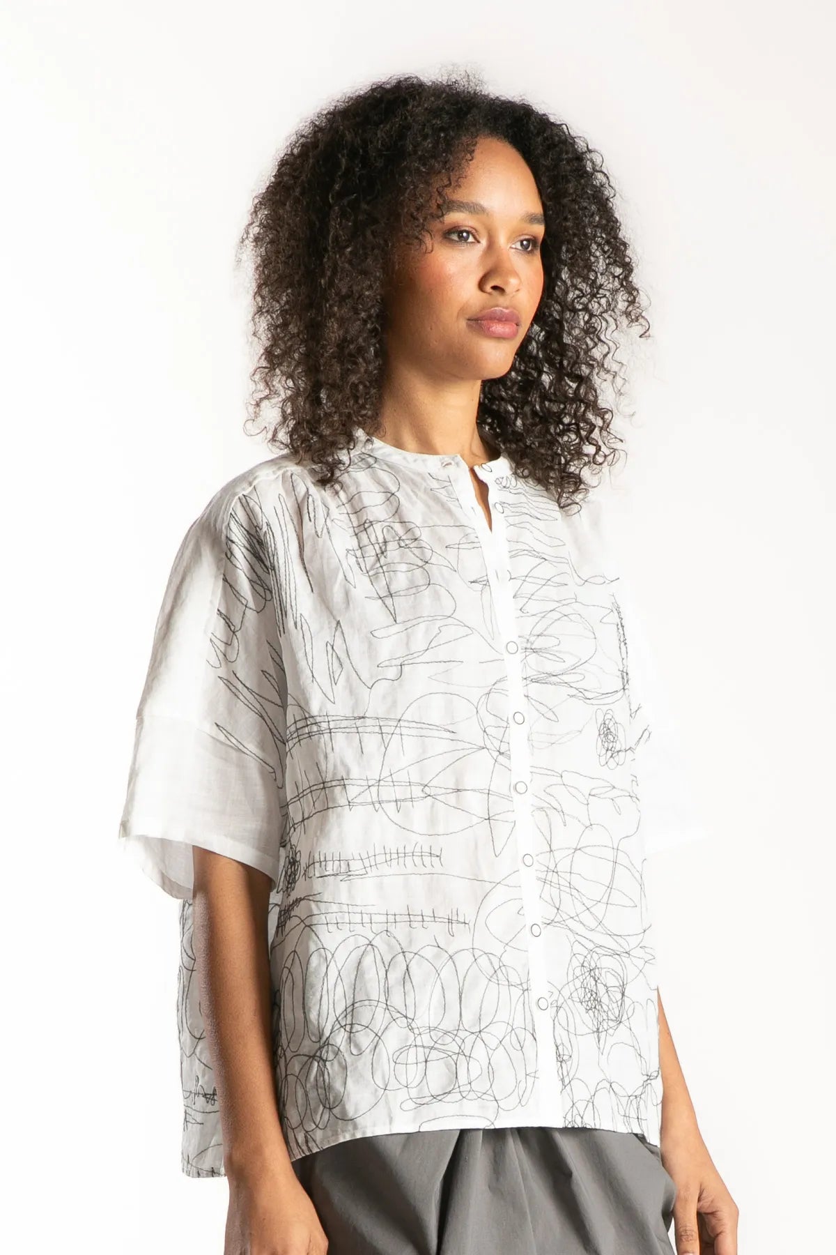 Ragga Blusa Frisia mao corte recto relajado manga corta de mujer en ramio blanco con bordado figuras grafito vista perfil