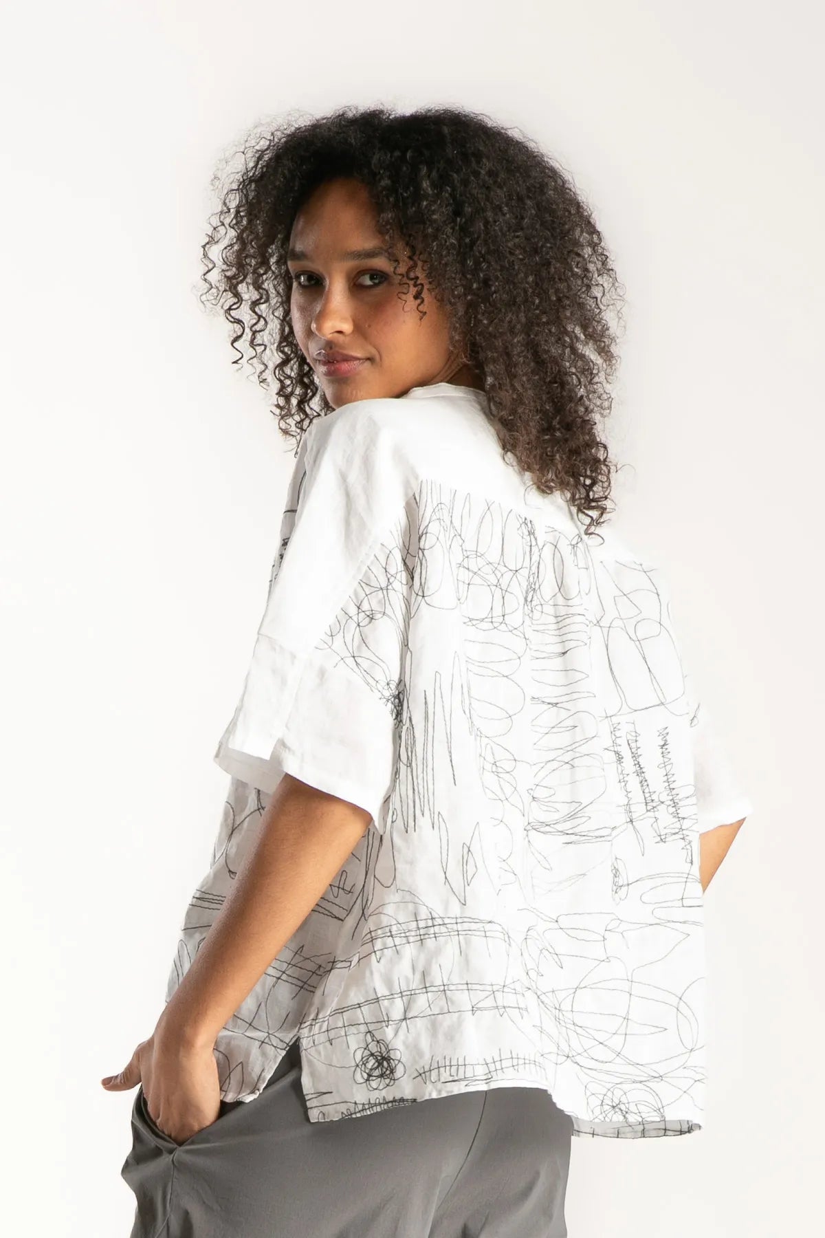 Ragga Blusa Frisia manga corta de mujer en ramio blanco y piezas con bordado figuras grafito vista perfil